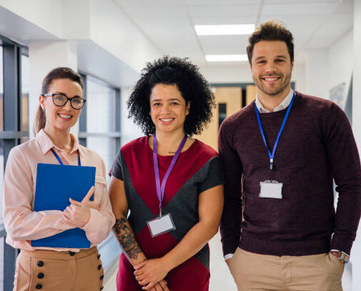 Portrait of three teachers in the school hall. They are smiling for the camera.